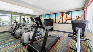 Een fitnessruimte met loopbanden, elliptische trainers en een hometrainer.