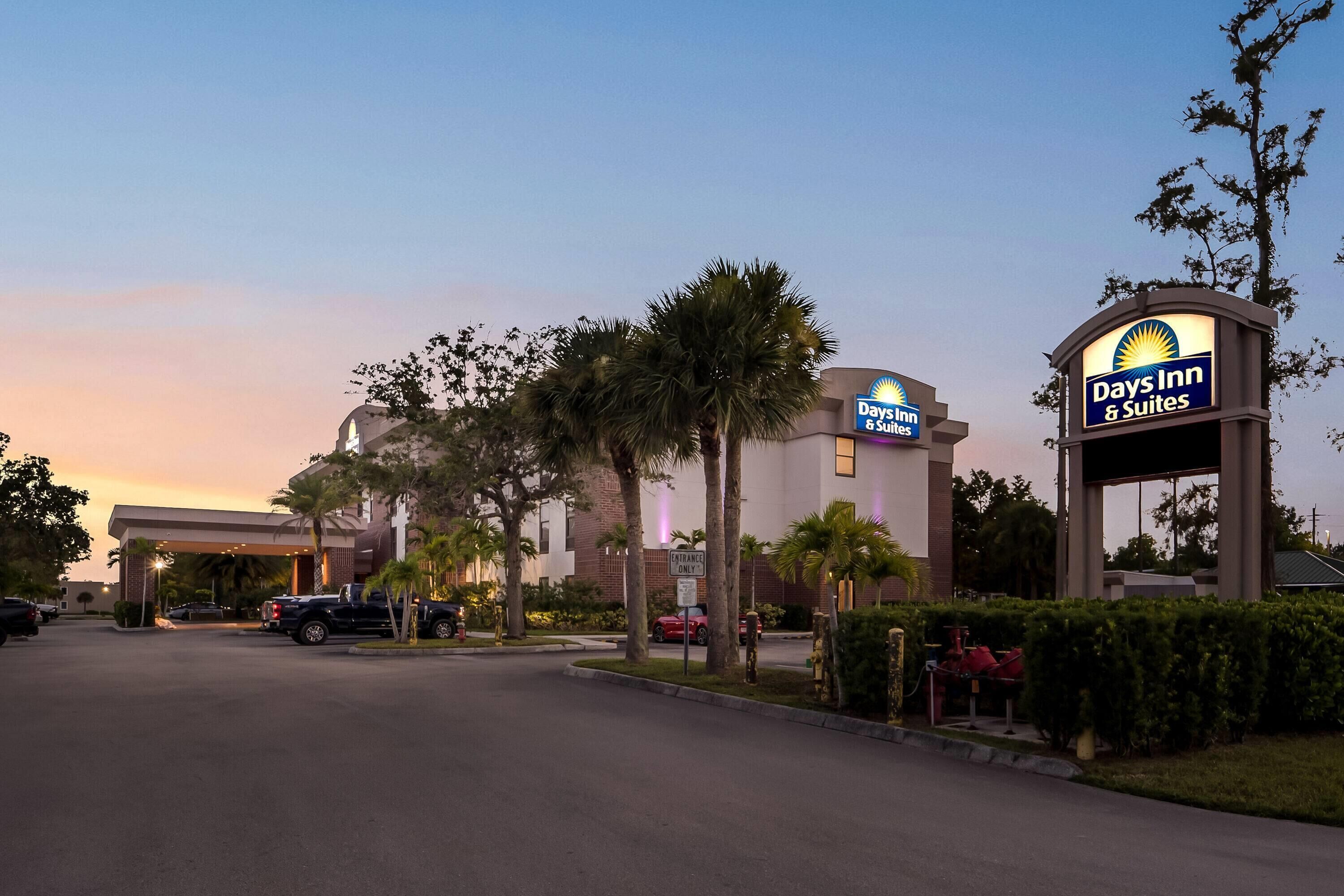 A Days Inn & Suites hotel with a clear entrance, palm trees, and a parking lot.