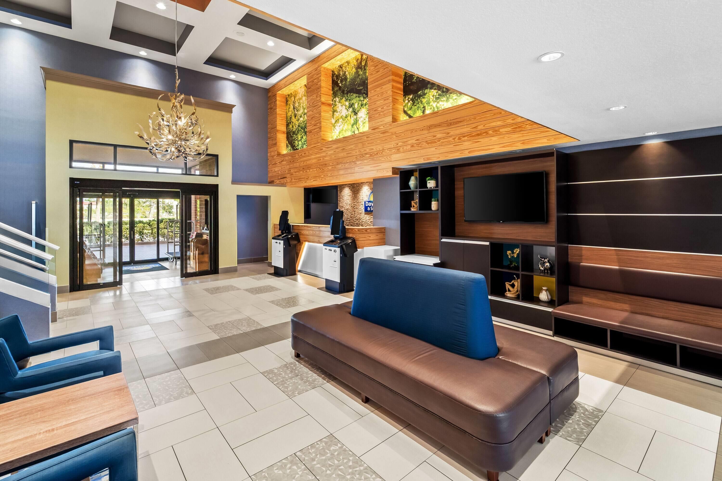 A modern lobby with a reception desk, seating area, and a large TV screen.