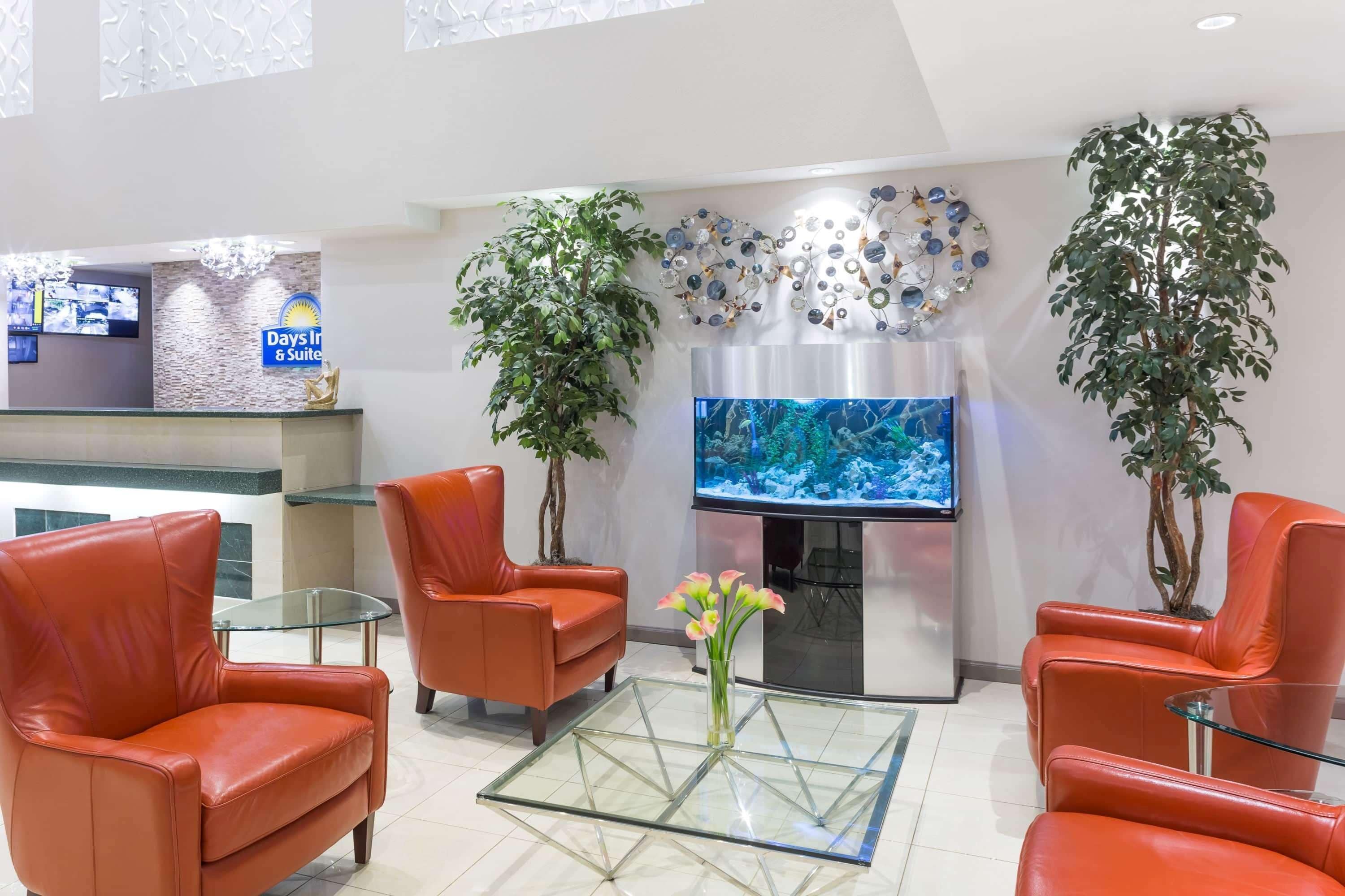 Un vestíbulo de hotel con sillones de cuero, una mesa de centro de vidrio, un televisor y decoración mural.