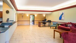 A reception area with a reception desk, a clock, a computer, and a seating area with a couch and chairs.