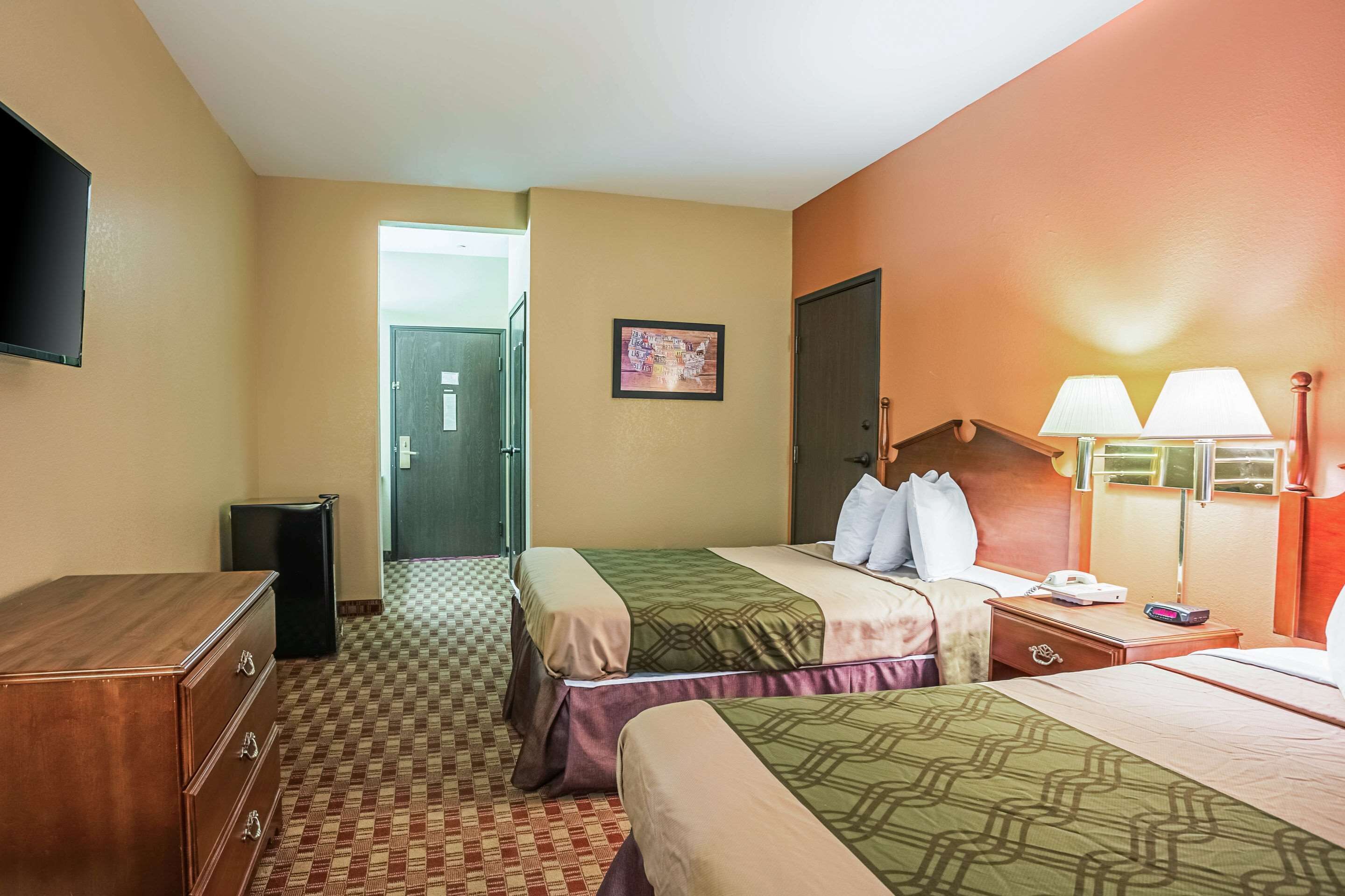 Una habitación de hotel con dos camas, un aparador, un televisor y una lámpara.