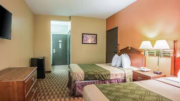 Una habitación de hotel con dos camas, un aparador, un televisor y una lámpara.
