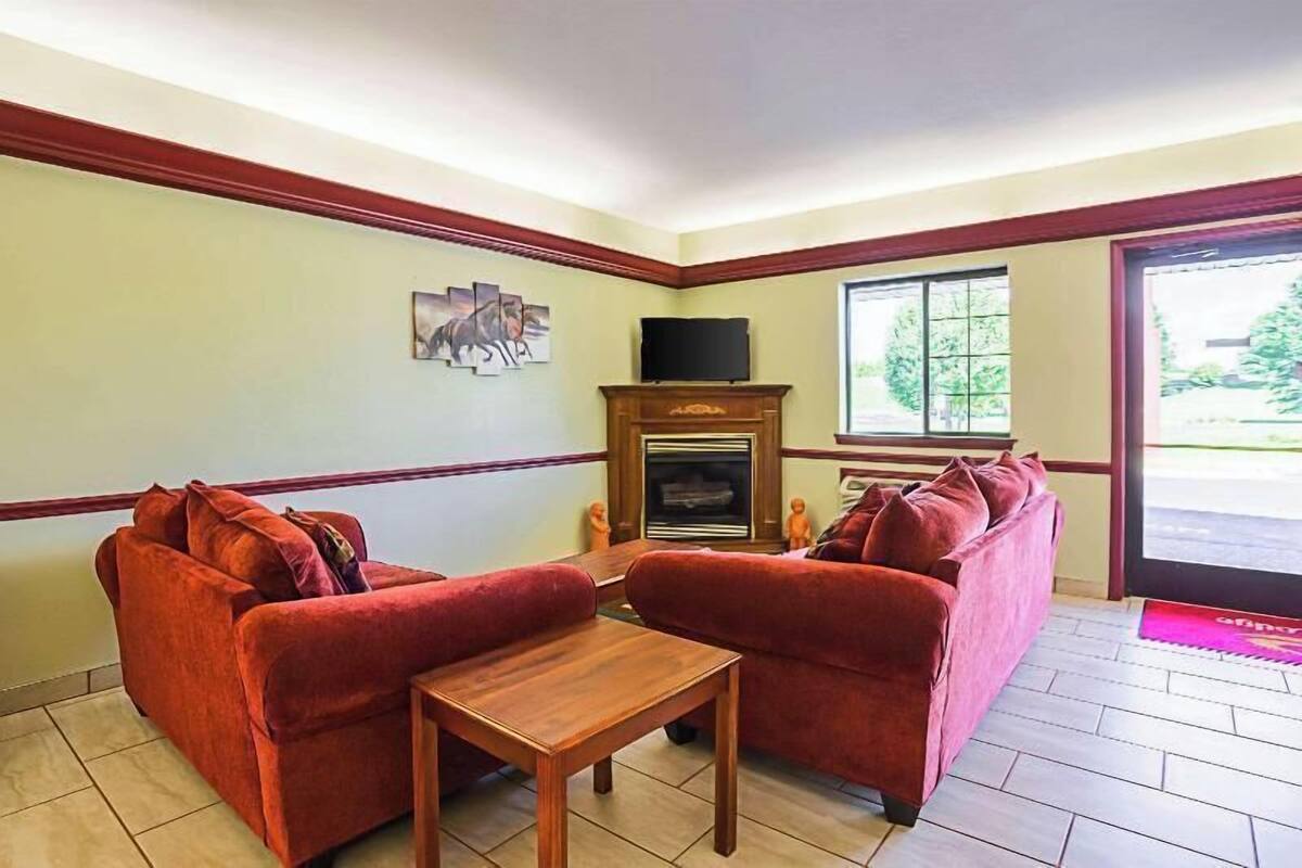 A living room with two red sofas, a wooden coffee table, a television, and a fireplace.