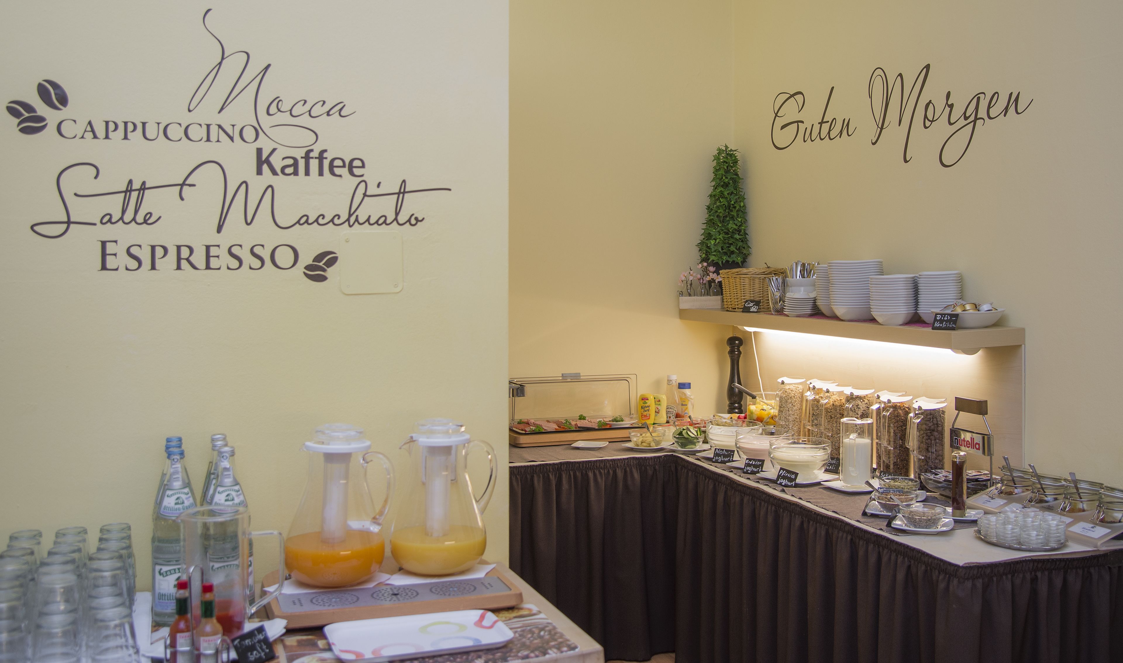 A breakfast buffet setup with labeled beverage options and a variety of food items.