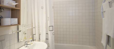 Une salle de bain avec un lavabo blanc, une baignoire et un rideau de douche.