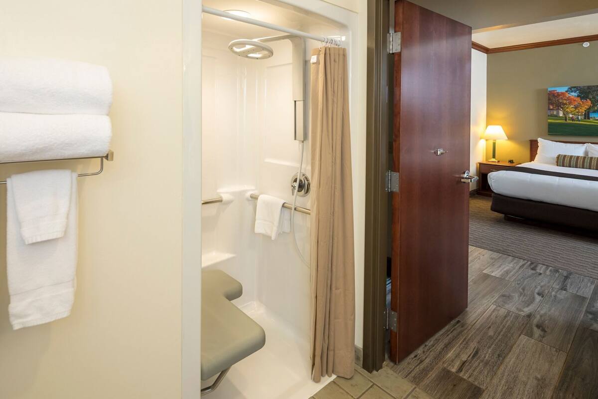 A hotel bathroom with a shower, toilet, and towel rack.