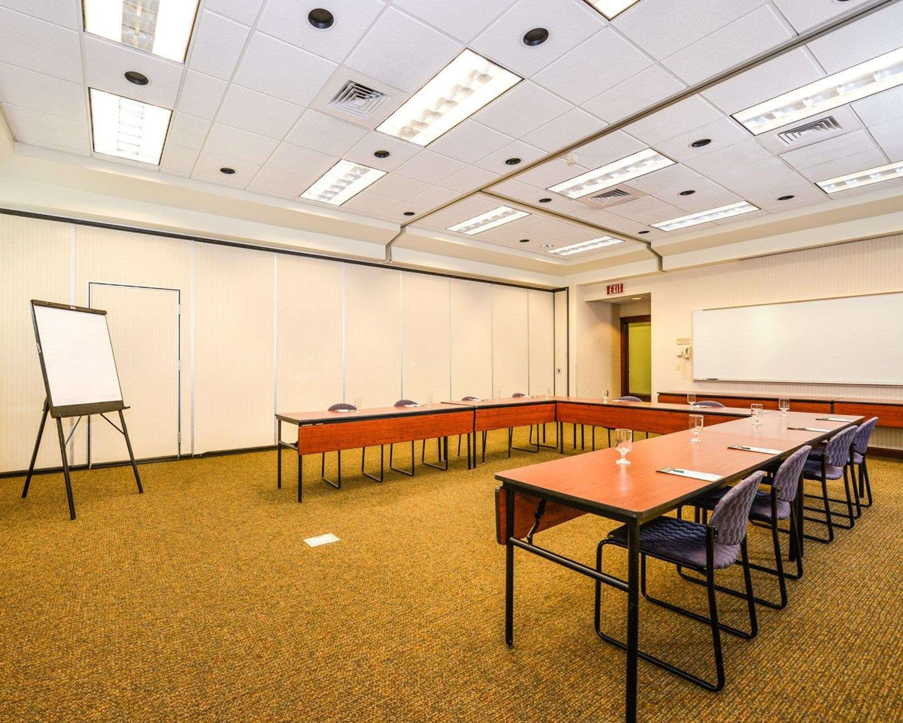 A conference room with a long table, chairs, a whiteboard, and a flip chart.