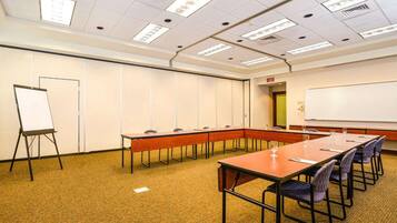 A conference room with a long table, chairs, a whiteboard, and a flip chart.
