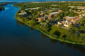 An aerial view of a campus with buildings, a river, and surrounding greenery.