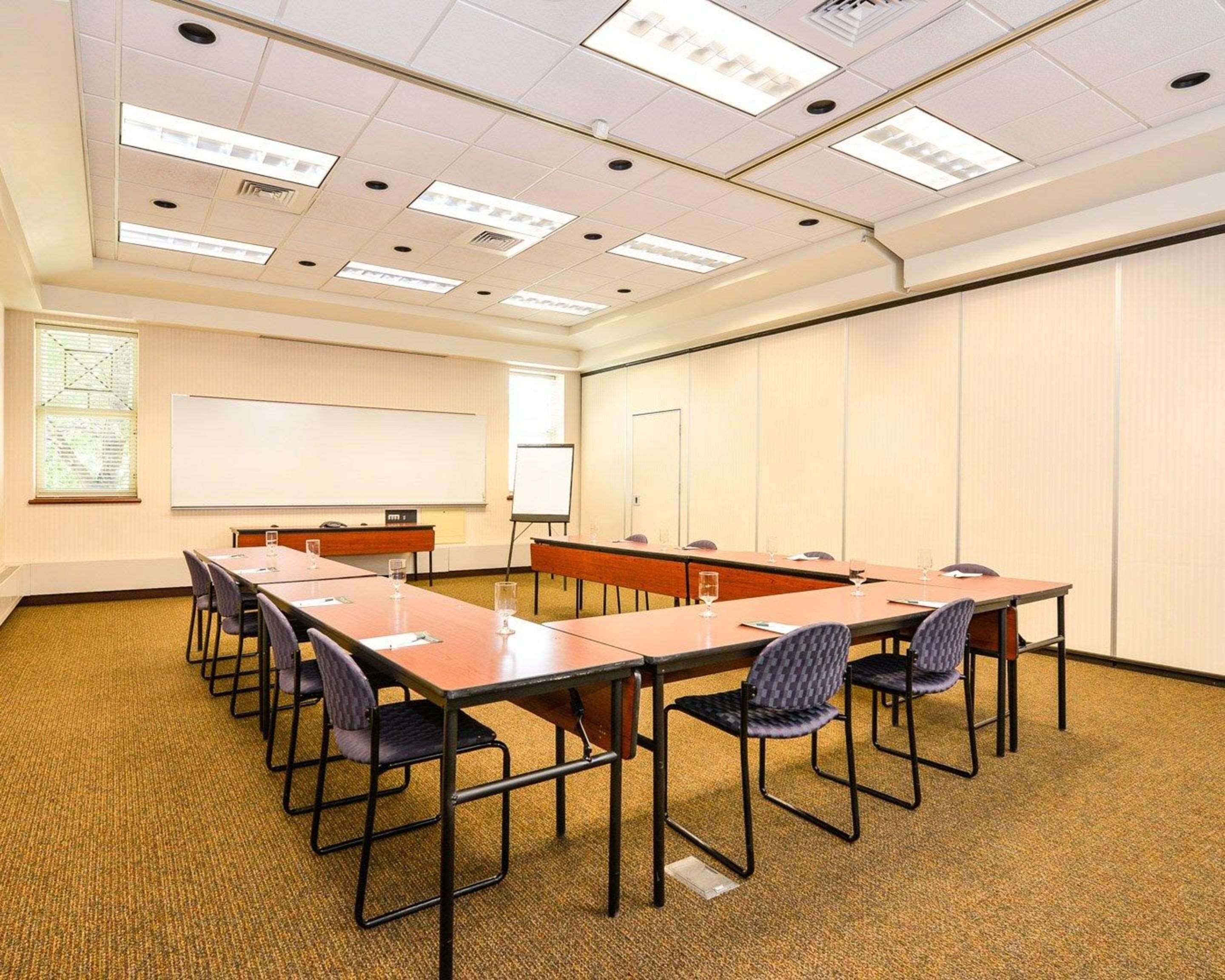 A conference room with a long table, chairs, a whiteboard, and a projector screen.