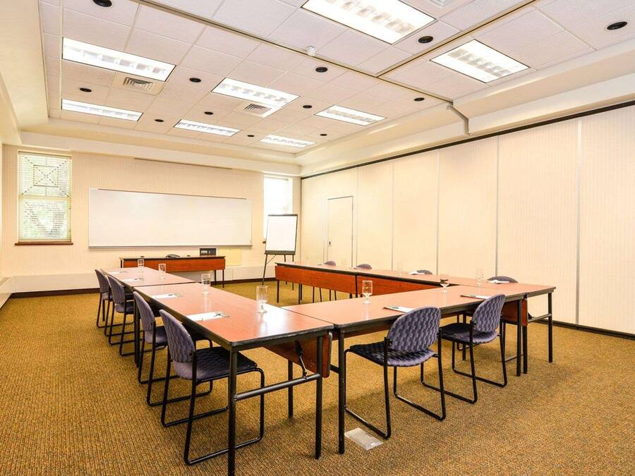 Une salle de conférence équipée d’une longue table, de chaises, d’un tableau blanc et d’un écran de projection.