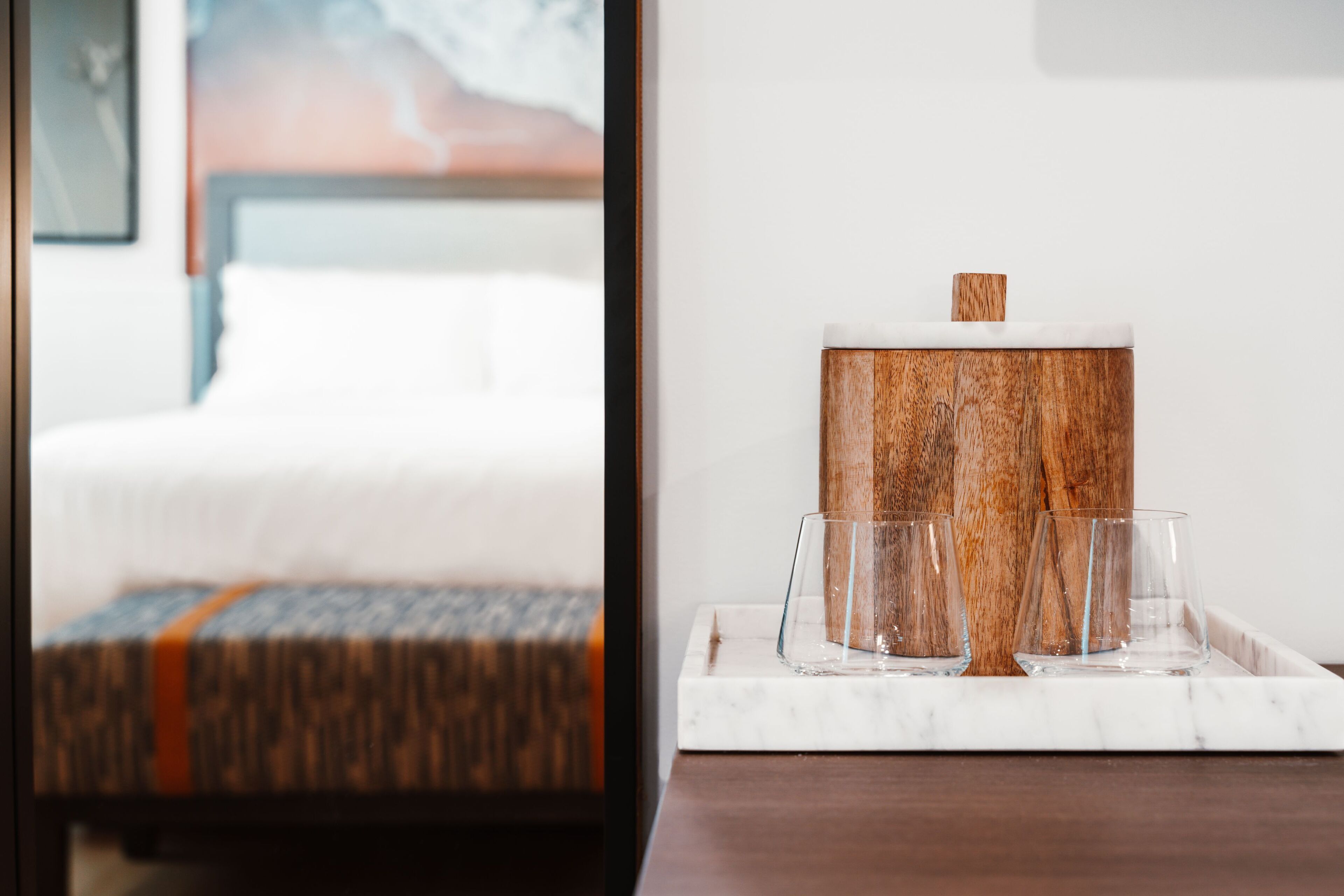 Ein Holztischchen mit Marmorplatte, auf dem drei klare Gläser und ein Holzbehälter stehen.
