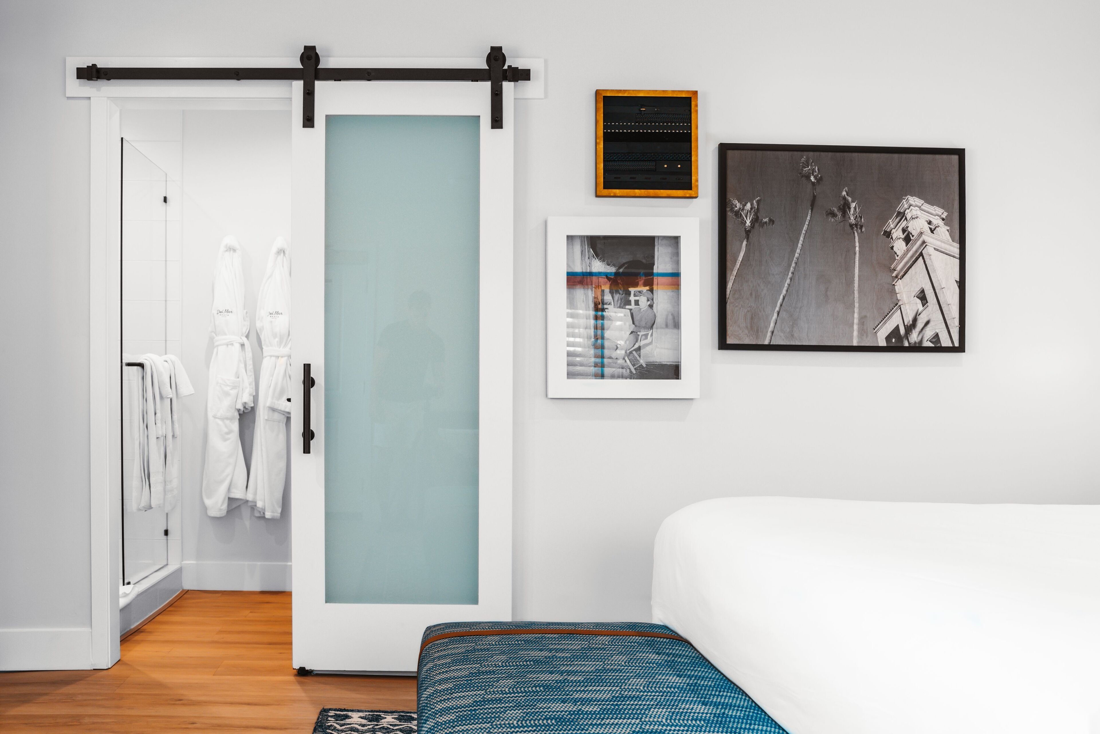 Een moderne hotelkamer met een schuifdeurkast, een bed, een ingelijst kunstwerk en een klein tafeltje.