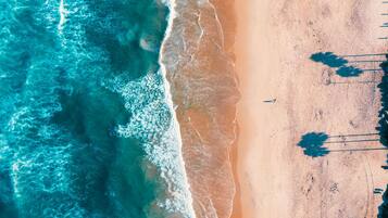 An aerial view of a beach with clear turquoise waters and a sandy shore.