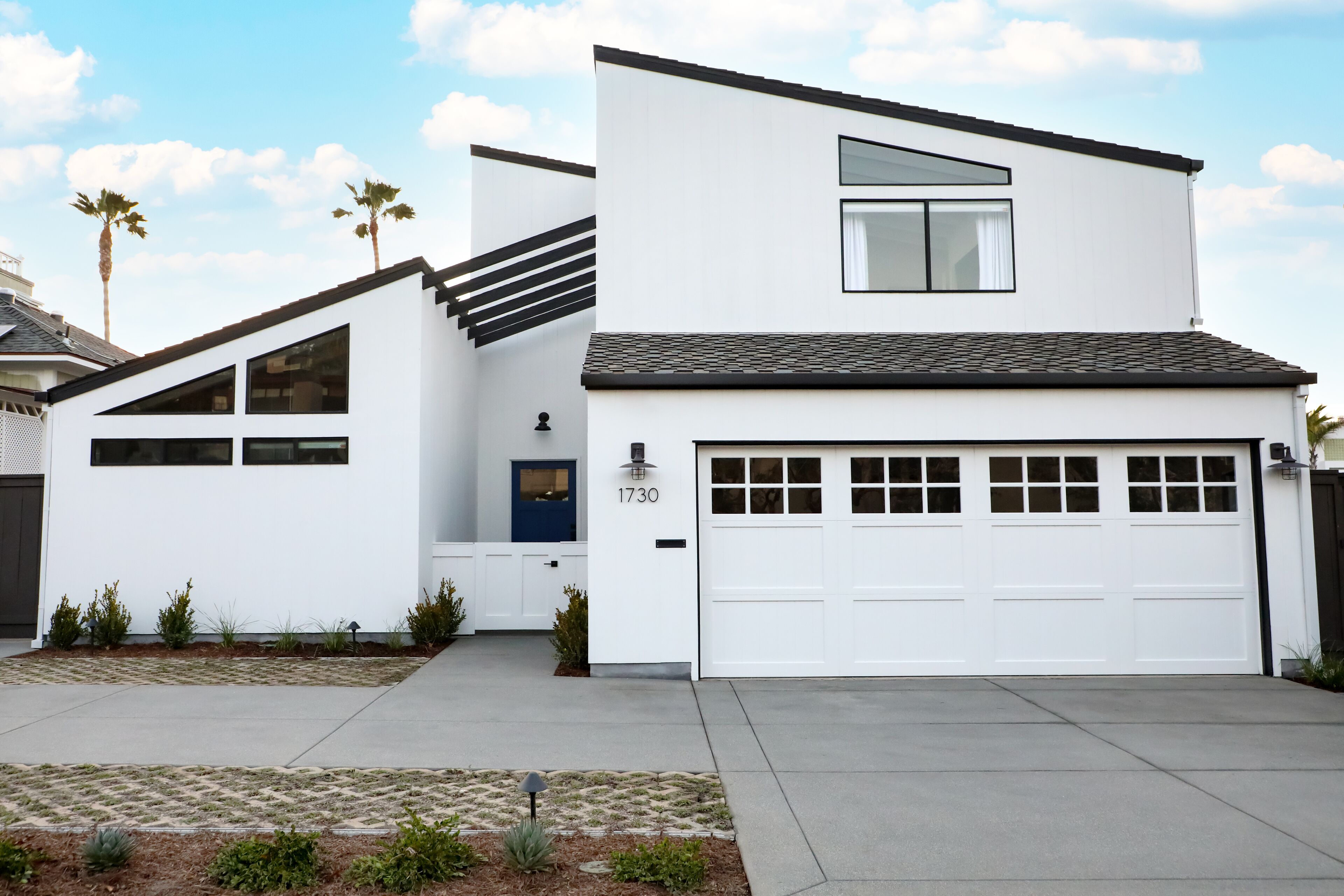 A modern two-story house with a white exterior, a garage, and a blue door.