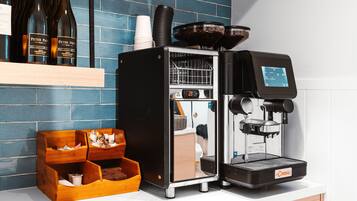 A coffee machine, a wooden coffee station, and wine bottles on a counter.