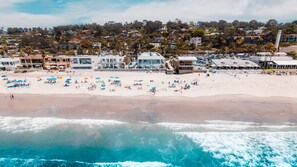 Vista aérea de una playa con numerosas sombrillas y gente.