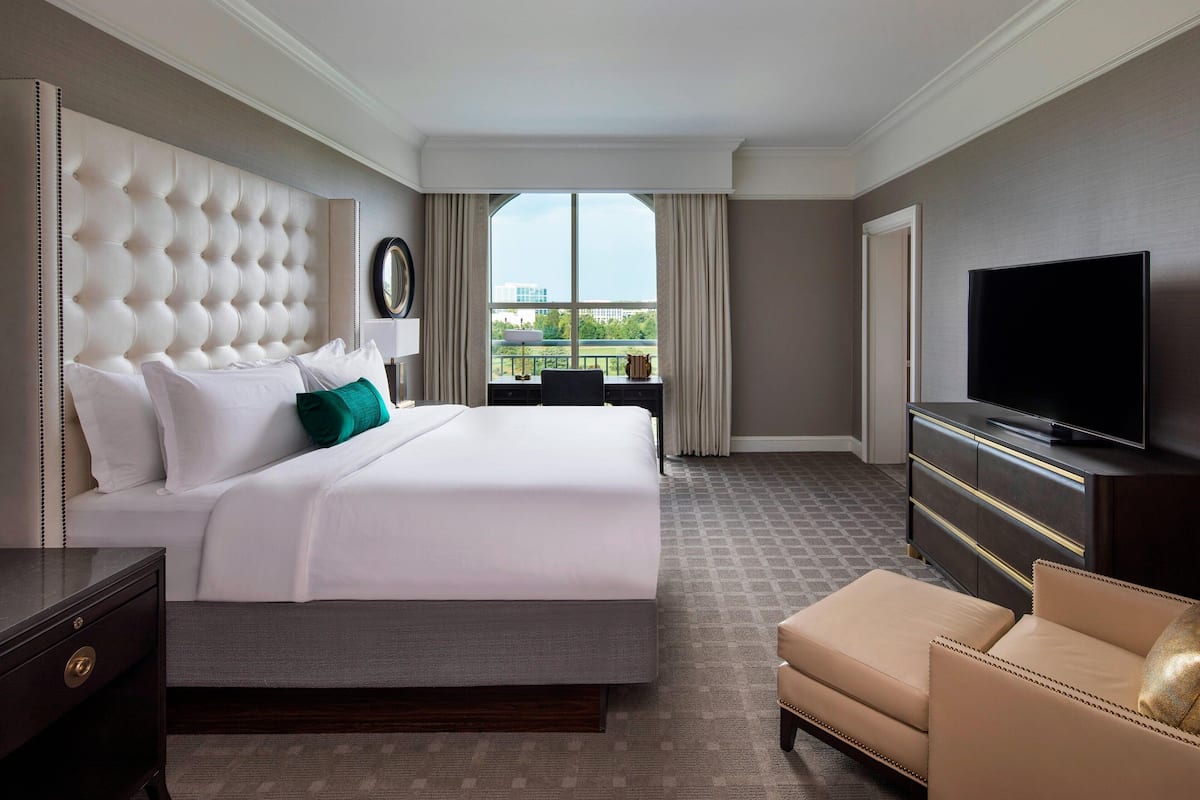 Une chambre d’hôtel avec un grand lit, une télévision, un bureau et une vue sur la ville.