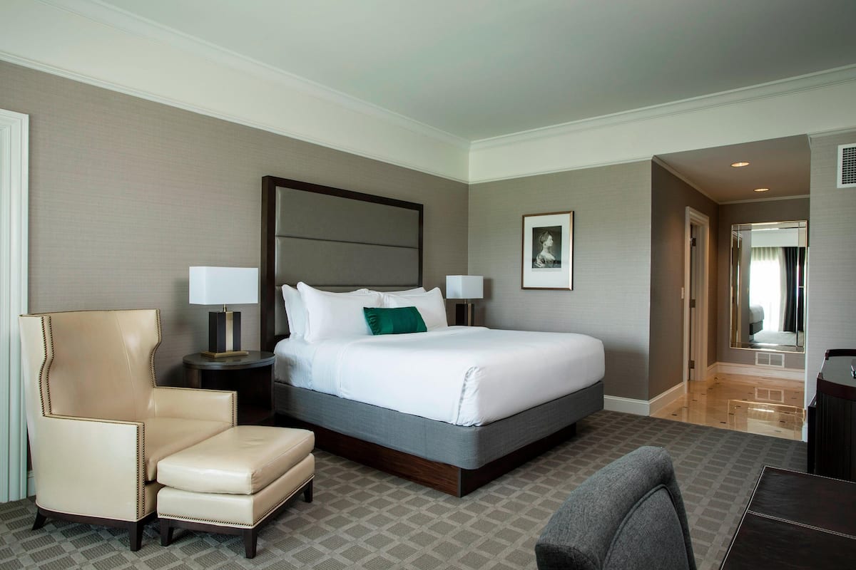 Une chambre d’hôtel avec un grand lit, une chaise, un bureau et un miroir.