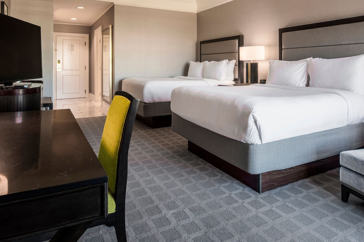 Une chambre d’hôtel avec deux lits, une télévision, un bureau et une chaise.