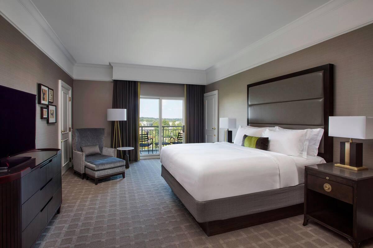 Une chambre d’hôtel avec un grand lit, un bureau, une chaise et un balcon avec vue.