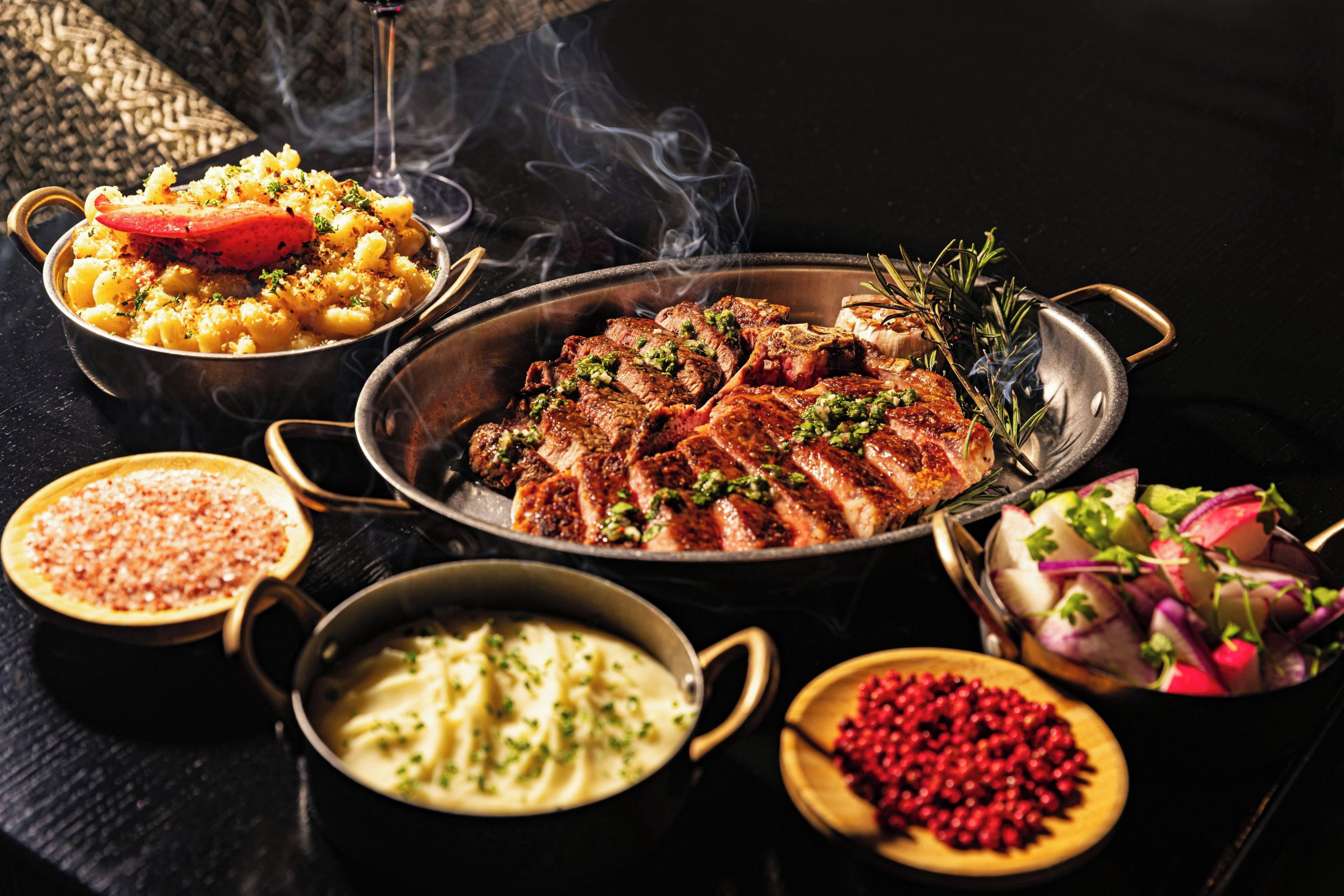 A variety of dishes including pasta, steak, and a salad, suggesting a meal setting.
