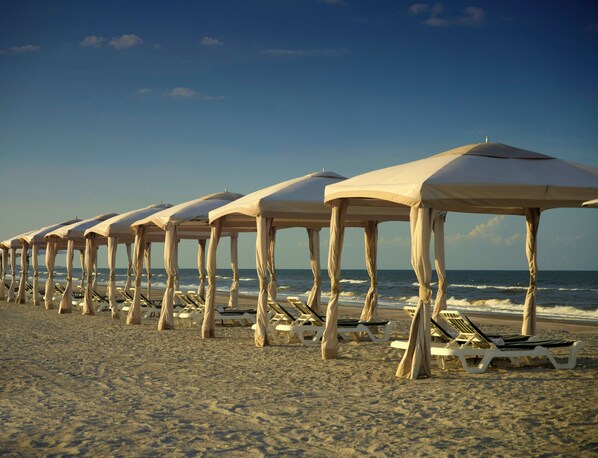 Uma praia com fileiras de guarda-sóis e espreguiçadeiras.