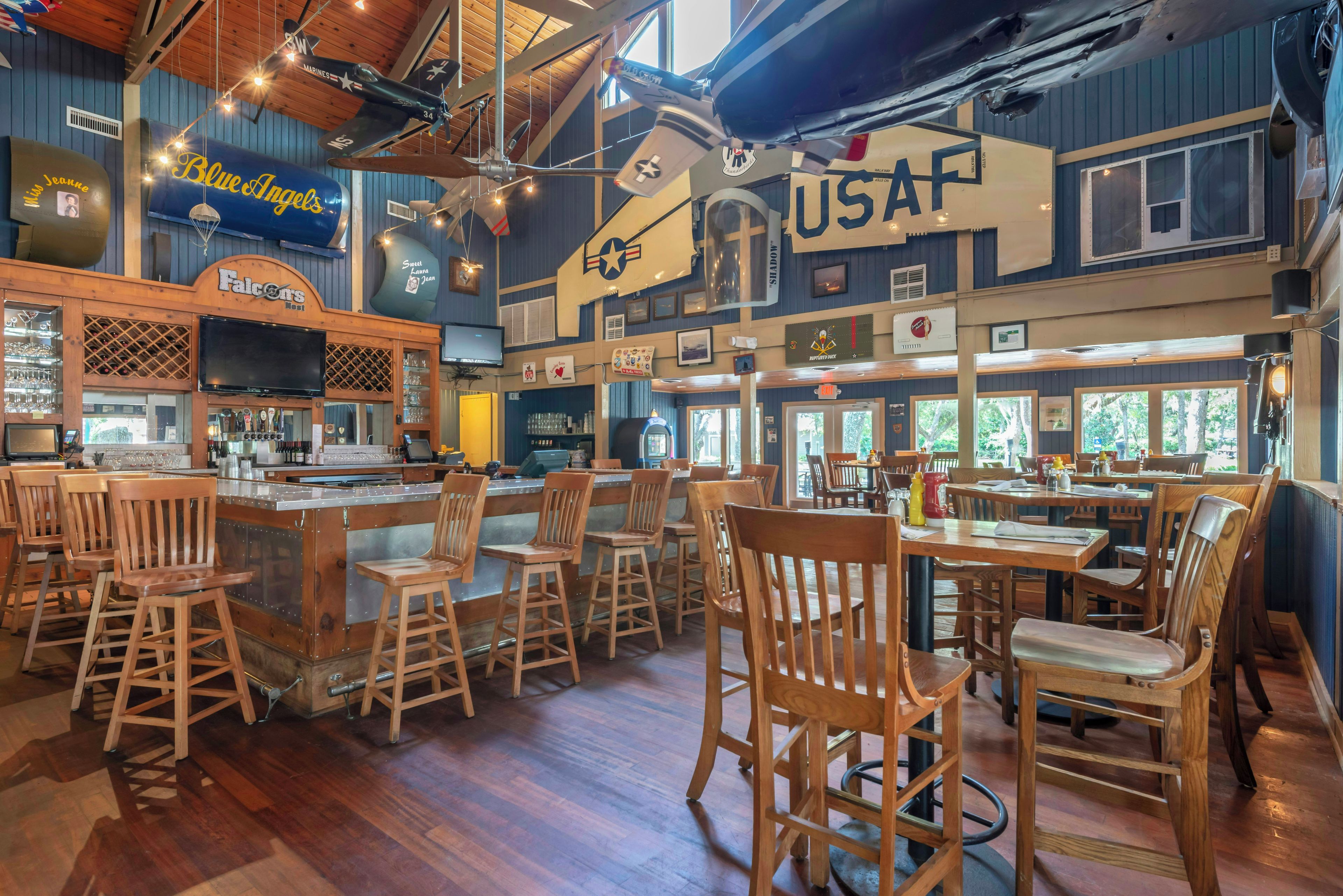 Un bar avec des chaises en bois et un comptoir, une enseigne indiquant « Falcons », et une grande enseigne « USAF » sur le mur.