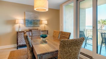 A dining area with a wooden table, woven chairs, and two wall-mounted lamps.