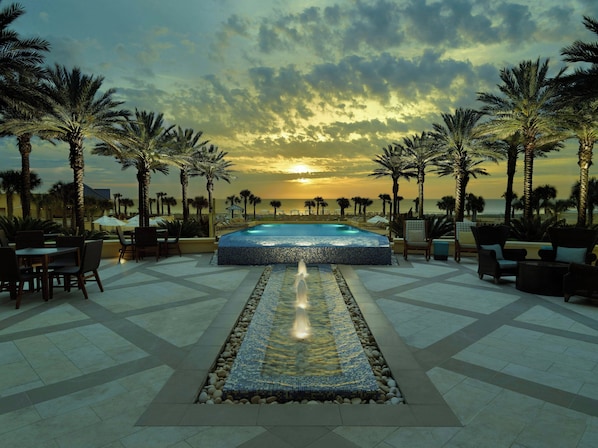 A pool area with a view of the sunset, surrounded by palm trees and lounge chairs. - The Villas of Amelia Island (Fernandina Beach)