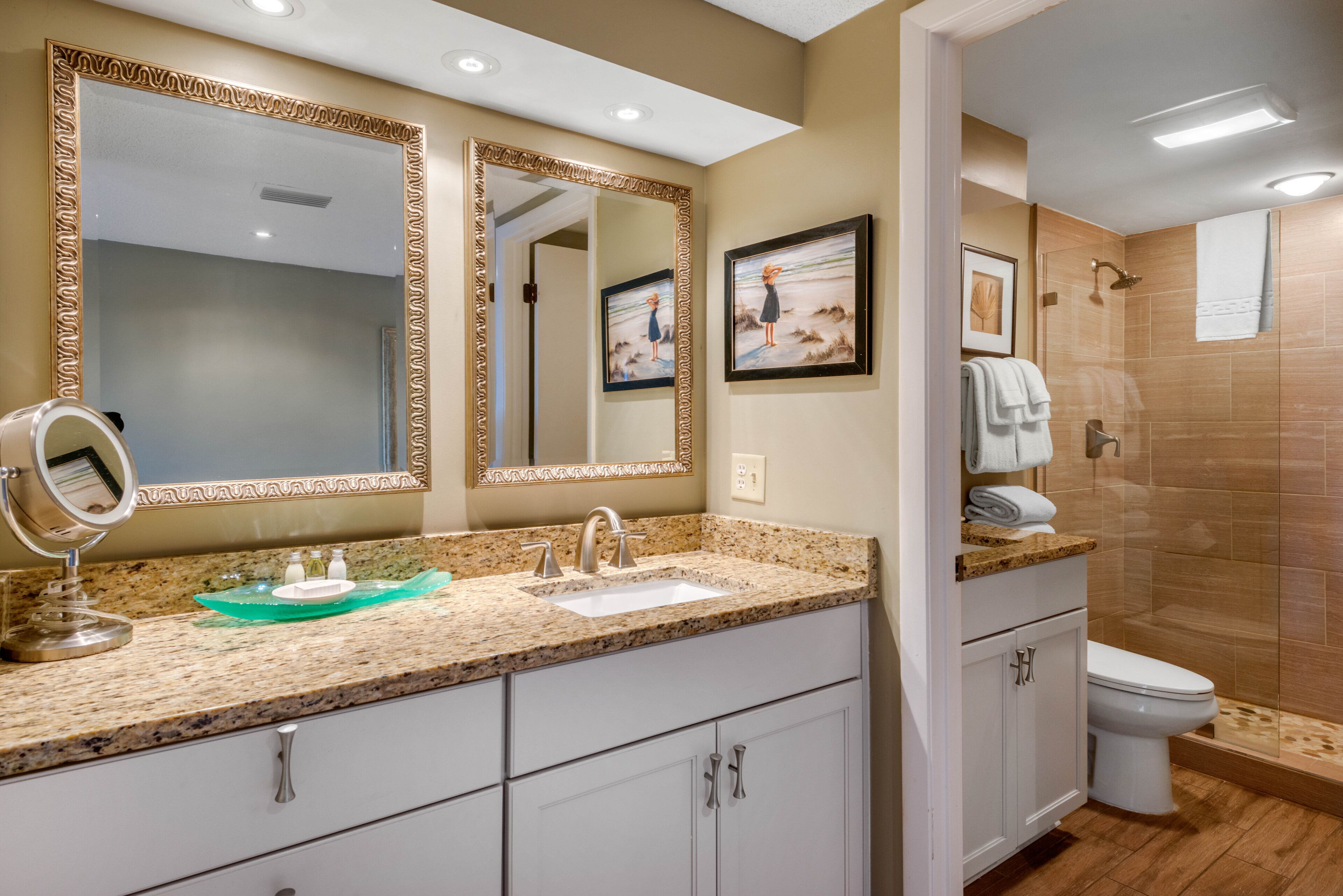 A bathroom with a granite countertop, a sink, a mirror, and a toilet.