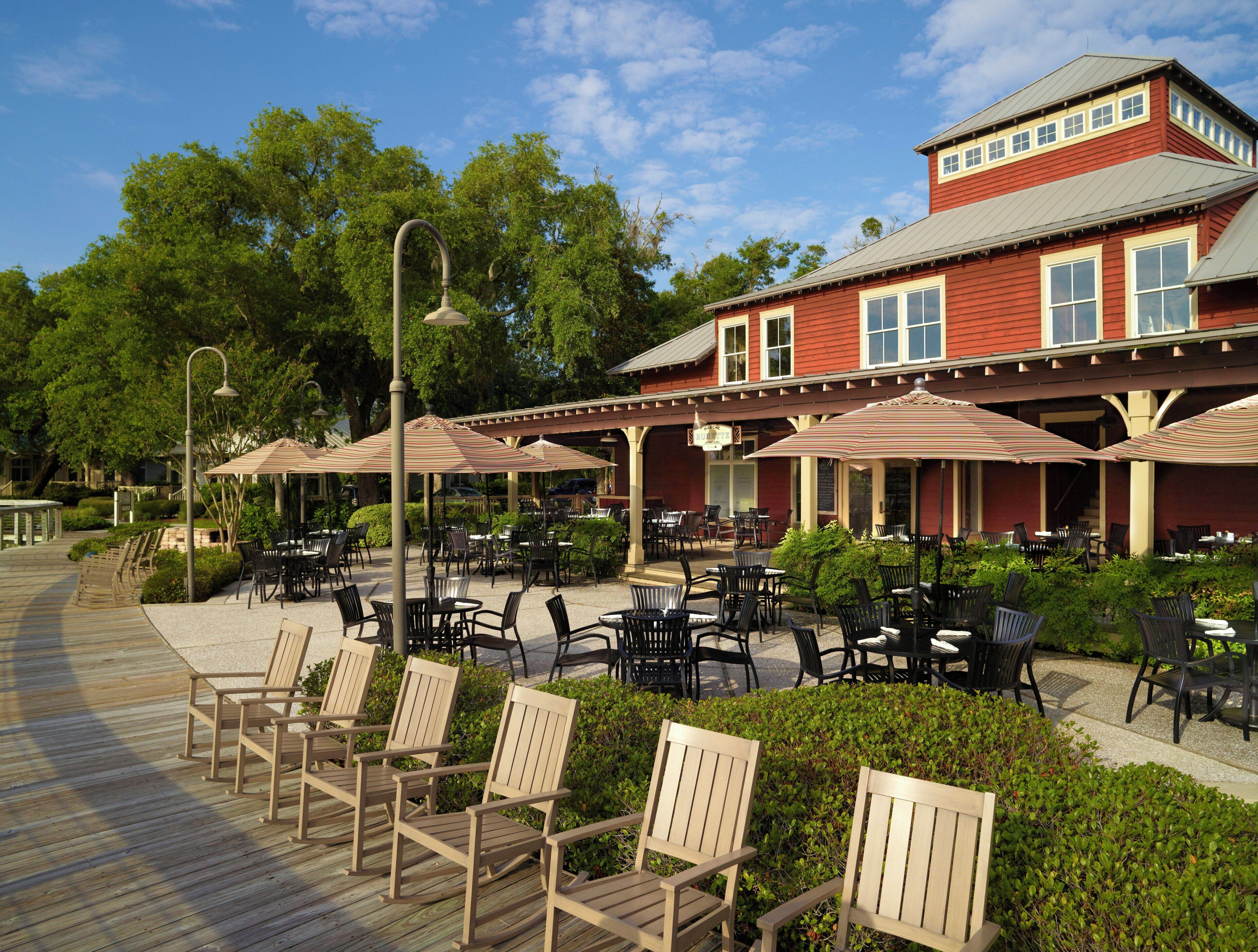 A wooden deck with outdoor seating, a red building with a gabled roof, and a clear sky.