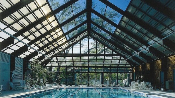 An indoor swimming pool with a glass ceiling and multiple lanes.