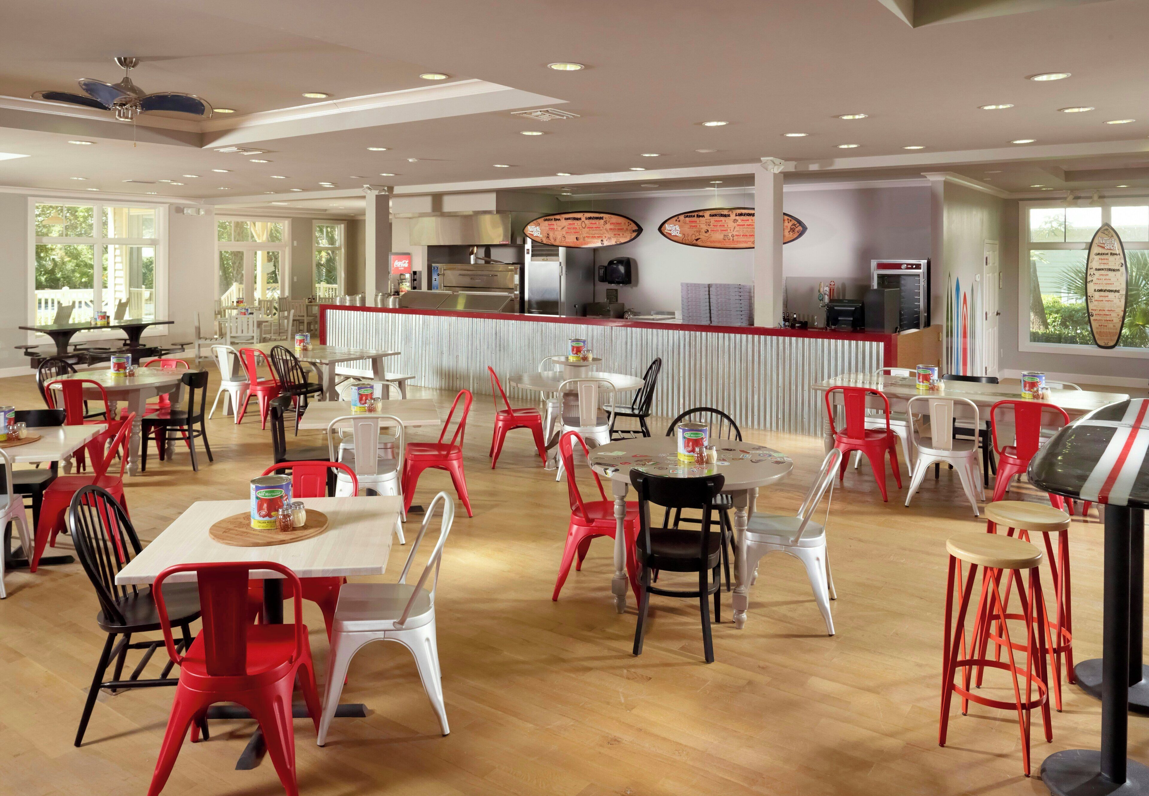 Een restaurant met meerdere tafels en stoelen, een toonbank en een menubord.
