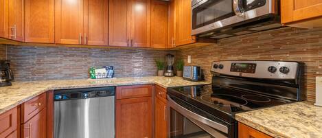 A kitchen with wooden cabinets, a stainless steel dishwasher, a microwave, a toaster, and a stove.