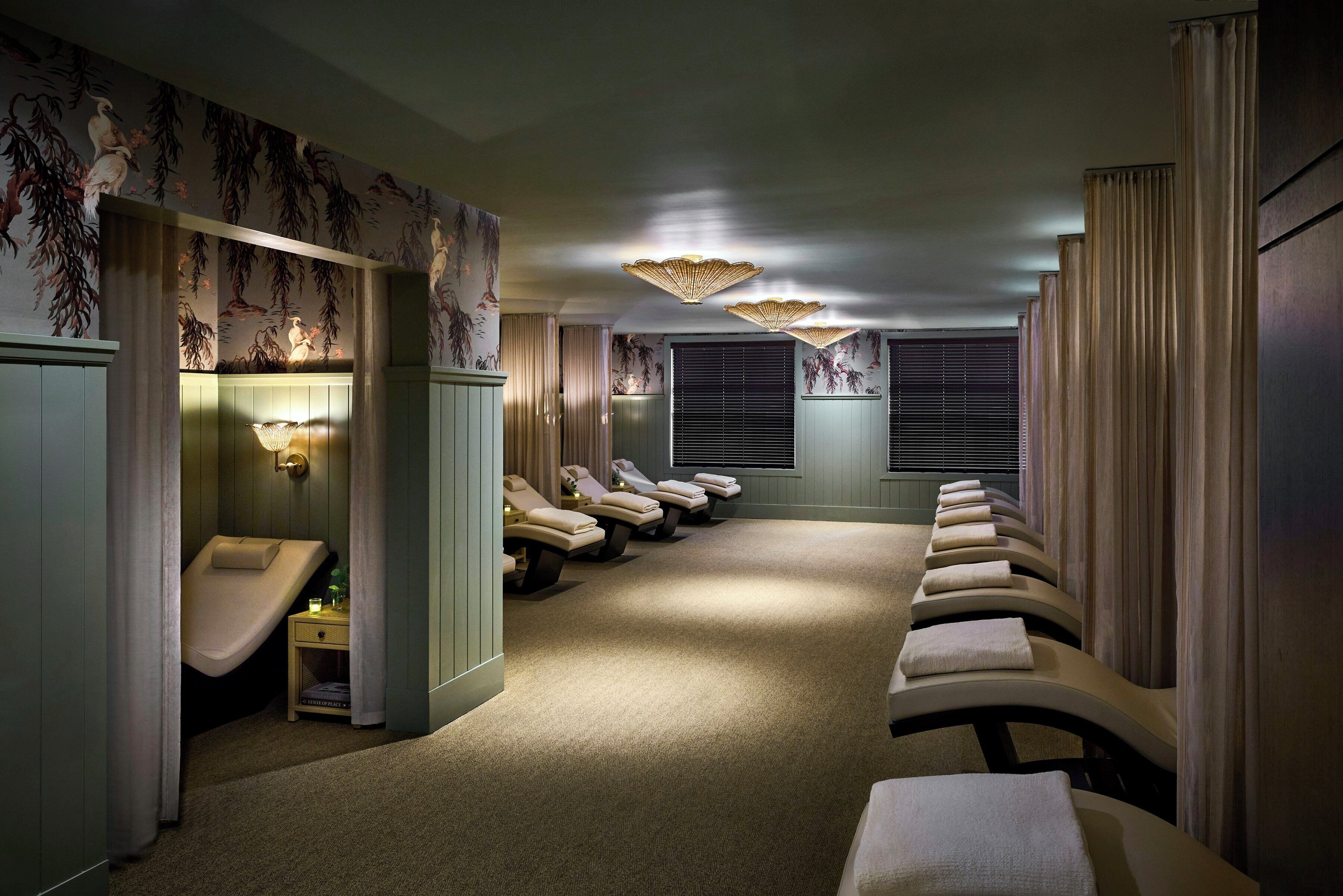 A spa room with massage chairs, a small sink, and a ceiling light fixture.