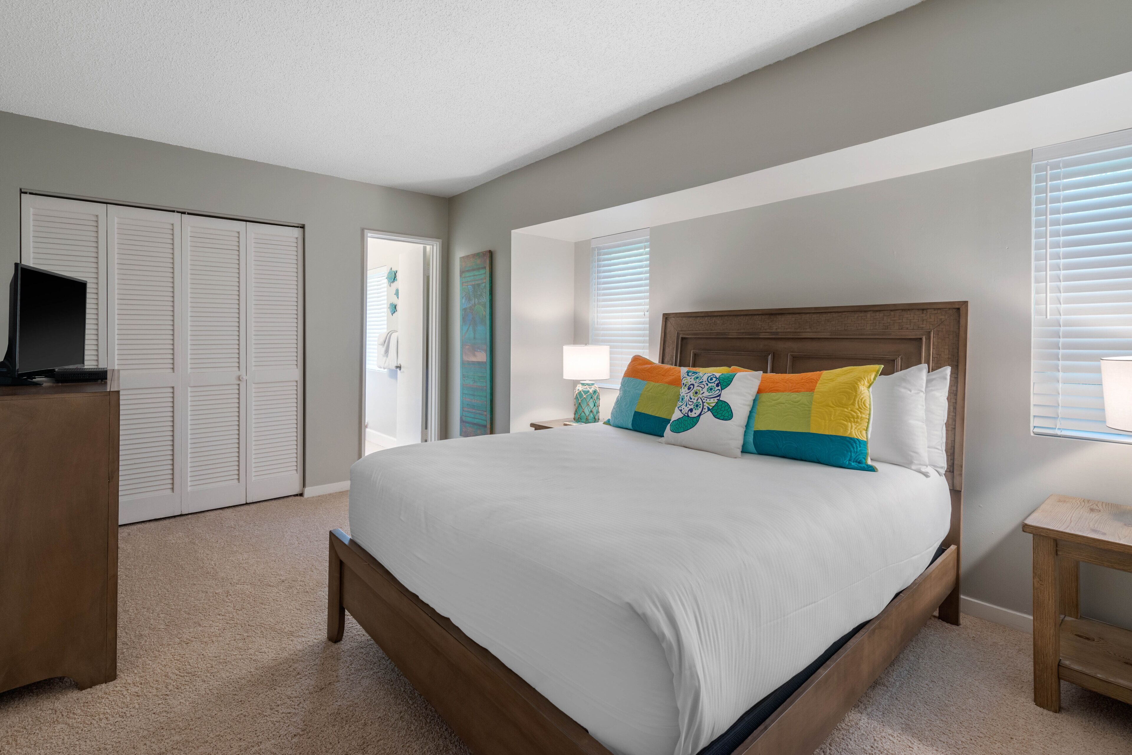 A bedroom with a bed, a desk, a TV, and a closet.