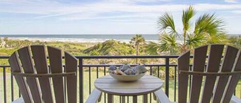 A balcony with two Adirondack chairs and a small table with a bowl.