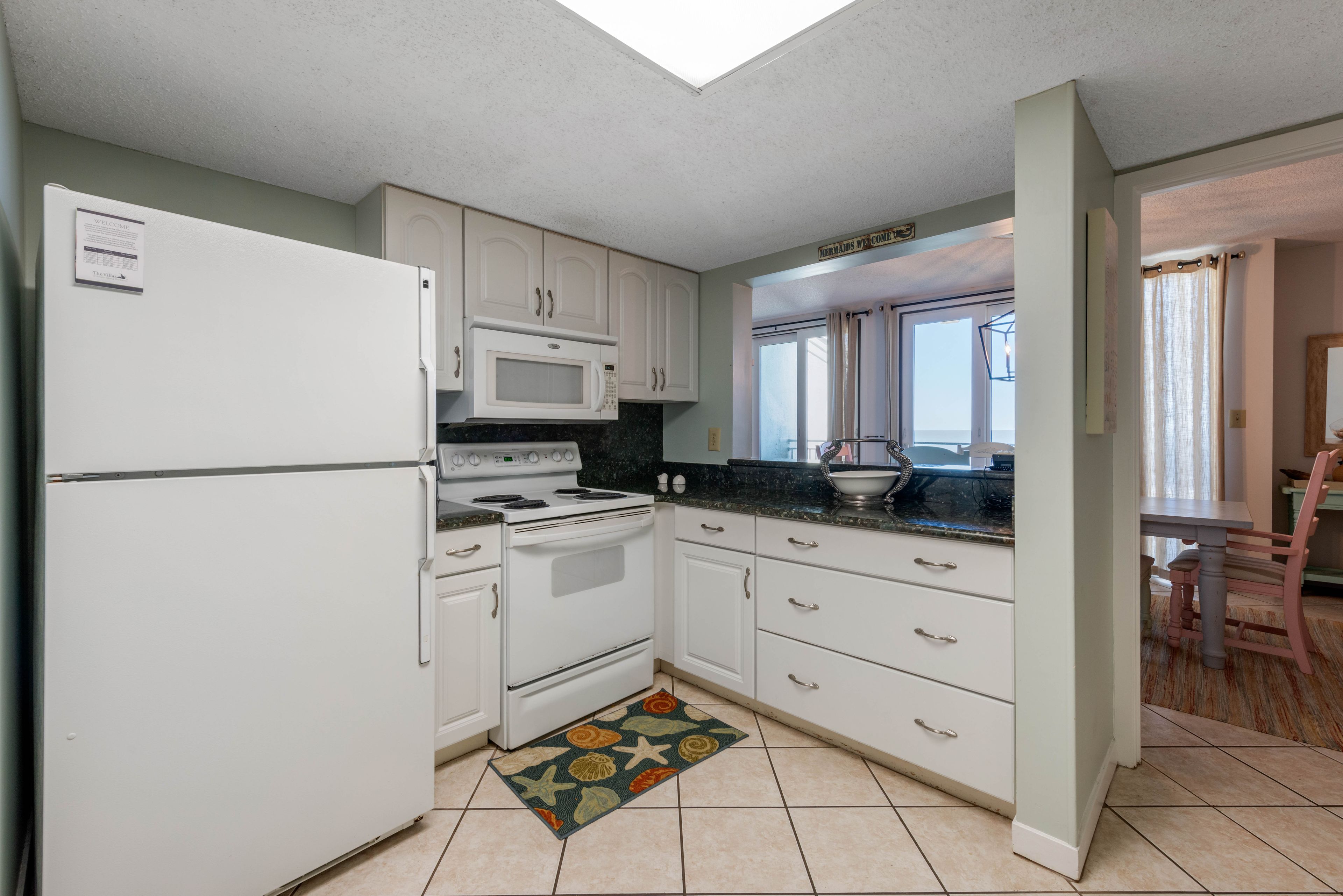 A kitchen with white cabinets, a microwave, stove, and a refrigerator.