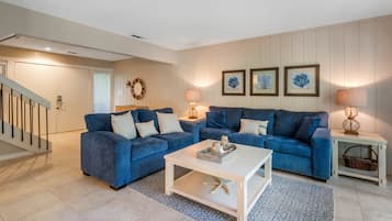 Un salon avec deux canapés bleus, une table basse blanche et un tapis à motifs.
