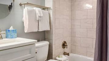 A bathroom with a toilet, sink, and bathtub. There are towels hanging on a rack and a shower curtain.