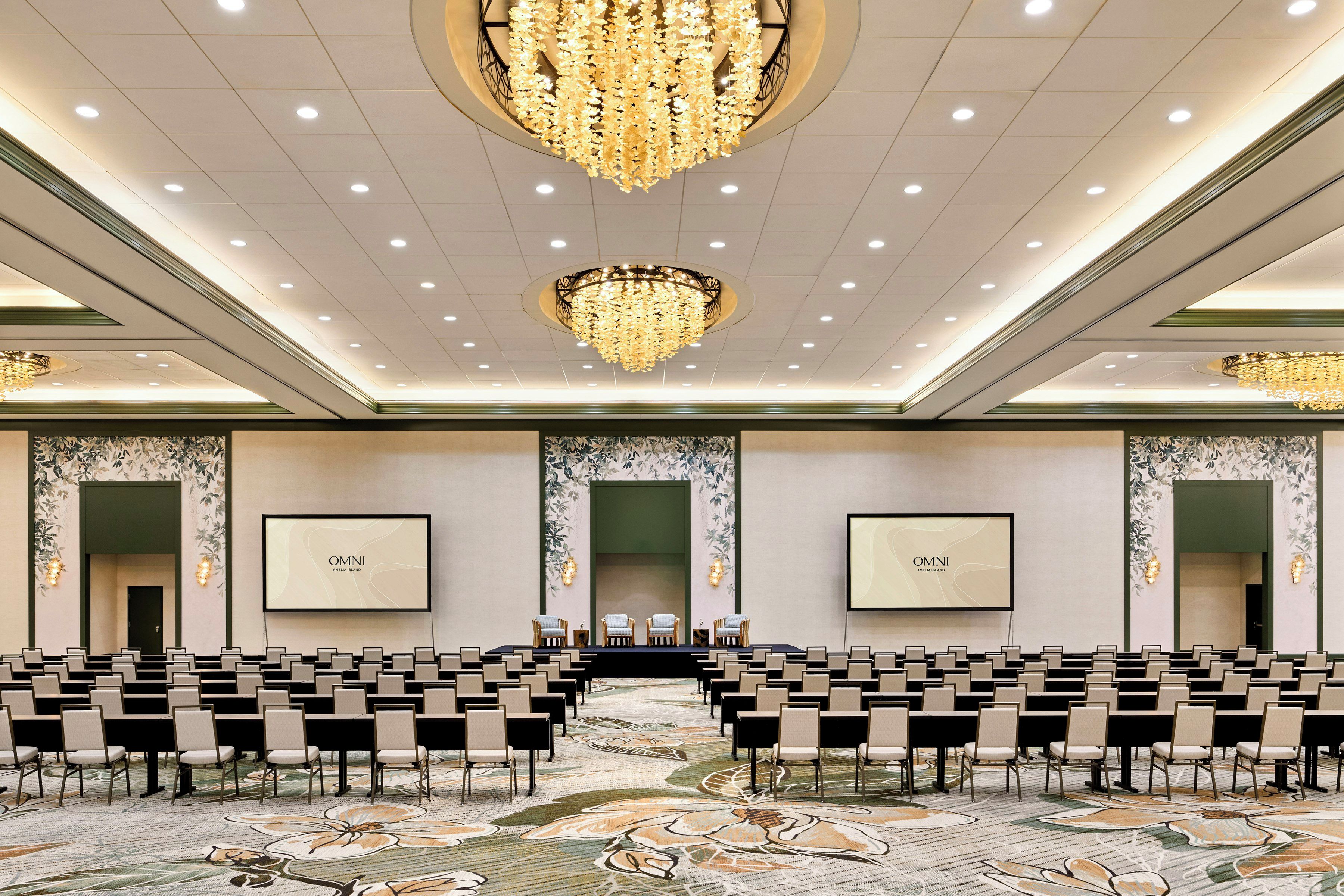 A conference room with rows of chairs, a stage, and two large screens displaying 'OMNI'.