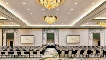 Uma sala de conferências com fileiras de cadeiras, um palco e duas telas grandes exibindo 'OMNI'.