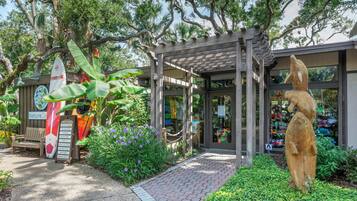 A garden entrance with a wooden bench, a surfboard, and a statue.