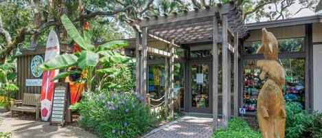 A garden entrance with a wooden bench, a surfboard, and a statue.