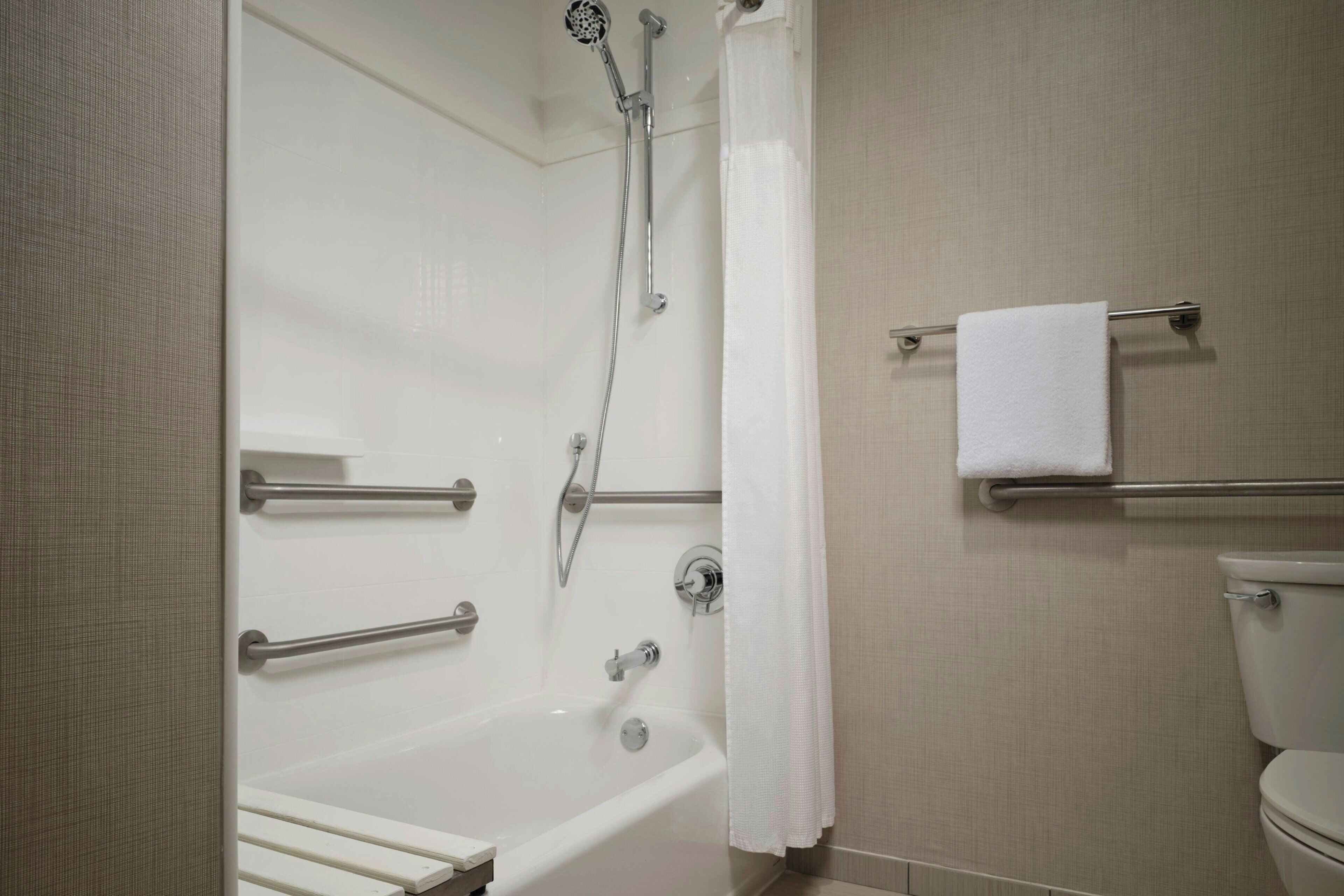 Een badkamer met bad, douche, toilet en handdoekrek.