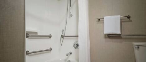 Een badkamer met bad, douche, toilet en handdoekrek.
