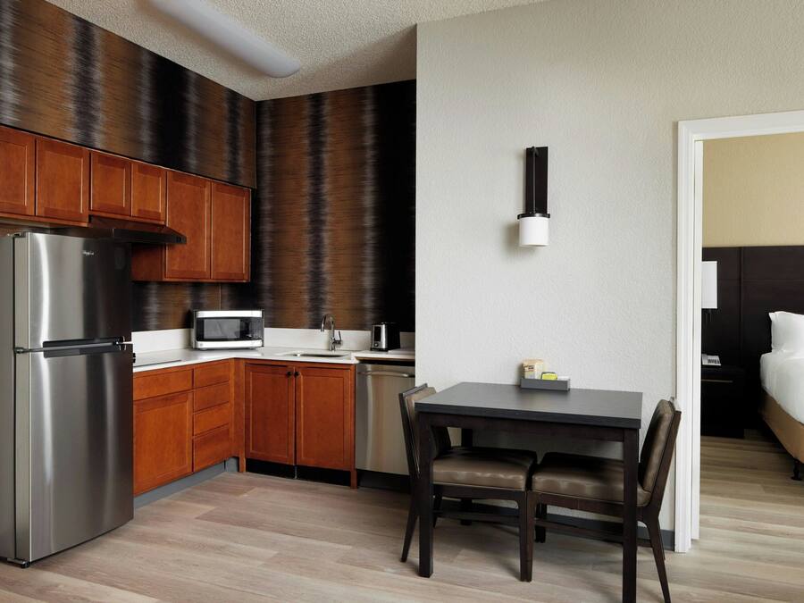 Ein kleines Hotelzimmer mit Küchenzeile, einem Bett, einem Essbereich und einem Badezimmer.