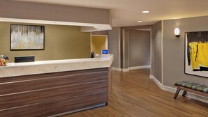 A reception area with a marble counter, wooden drawers, and a bench.
